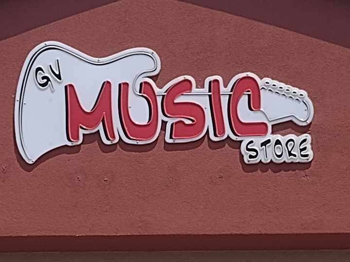 Store sign with the words 'Music Store' inside an electric guitar graphic on a red background.