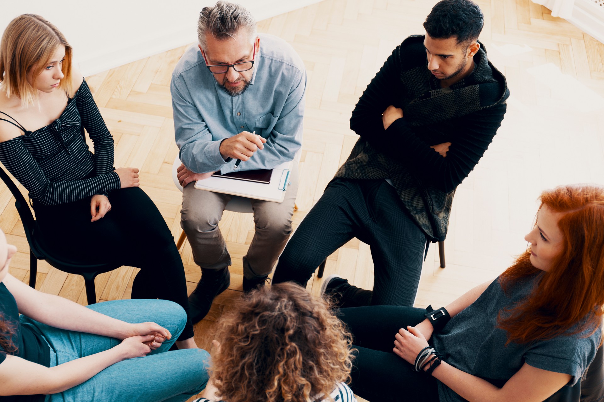 Experienced psychotherapist explaining the healing process to a woman with anger management issues during group therapy session