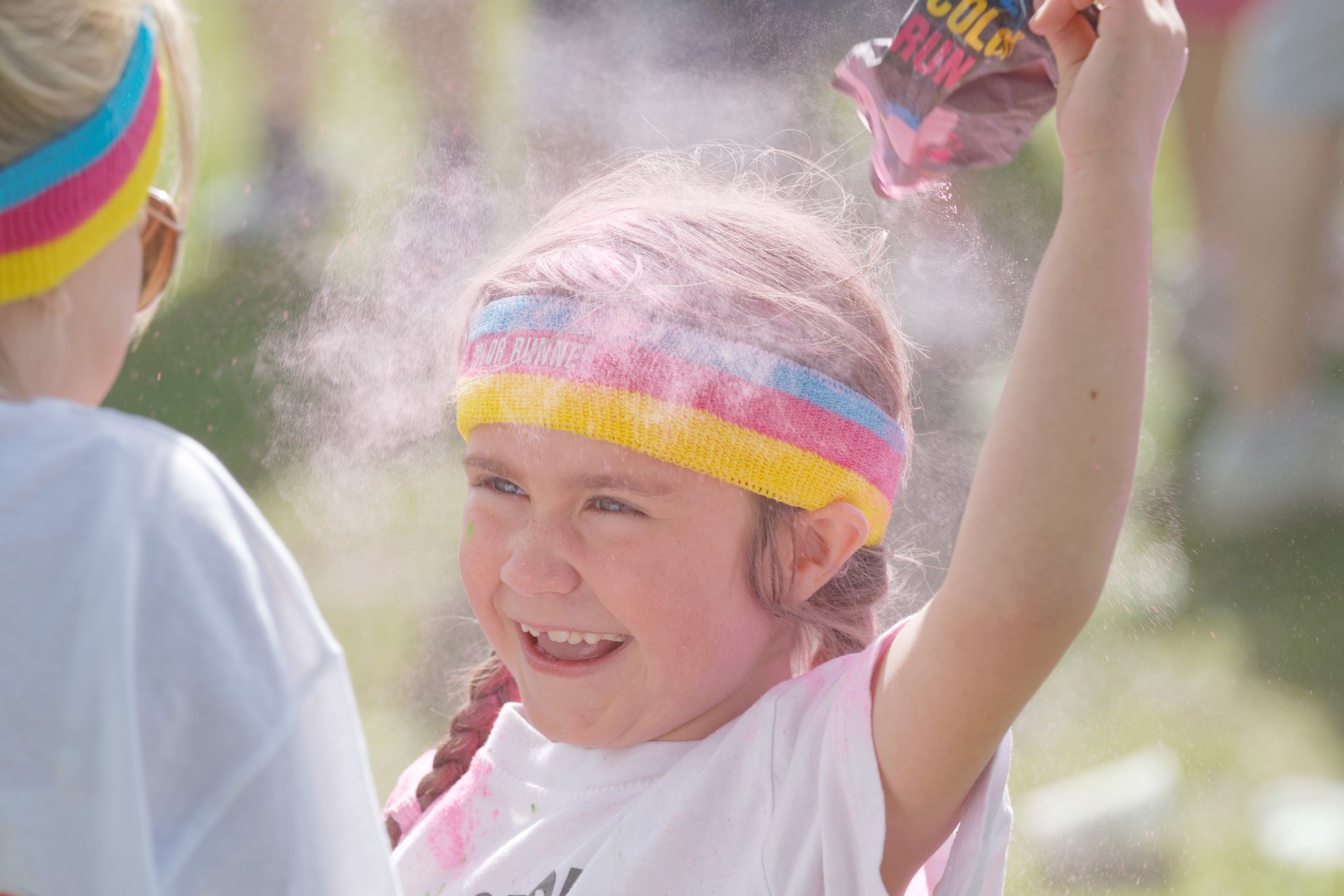 Happy kid squirting pink color powder over the head