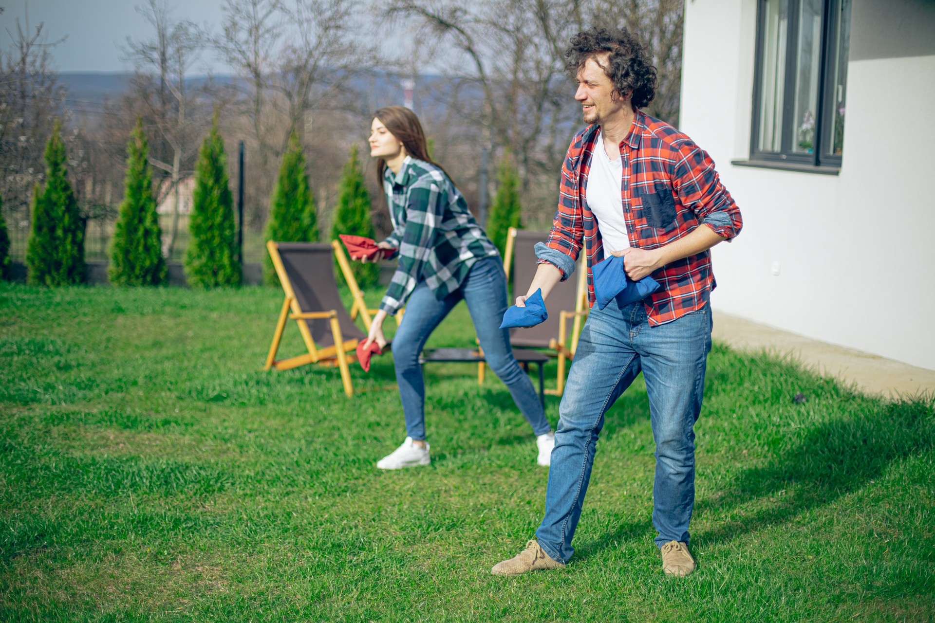 Backyard party, couple playing cornhole bean bag toss game